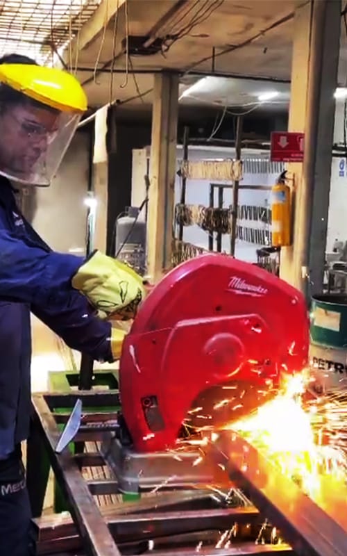 Operario realizando corte de perfiles metálicos con sierra industrial en taller metalmecánico Metaloide S.A.S en Medellín